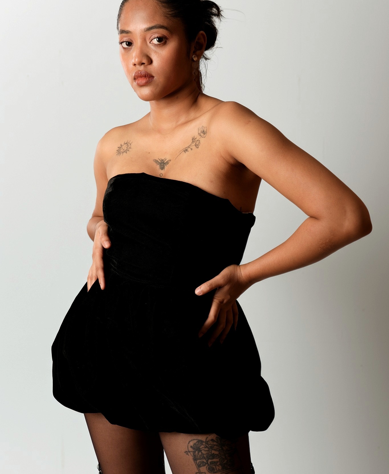 Model posing in a sculptural black mini dress